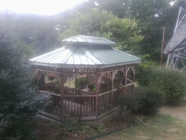Green metal roof on a backyard gazebo surrounded by garden beds in West Columbia