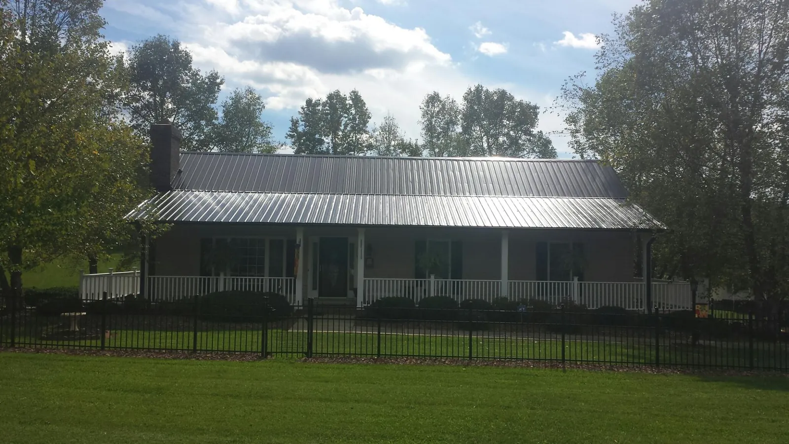 Gray metal roof on a brick ranch with a full width front porch — Gutter Guard Installation work by our crew in West Columbia